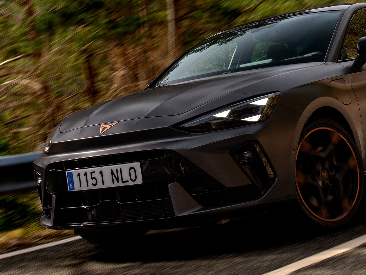 CUPRA Leon SP riding along a wooded road, showcasing its front design details.