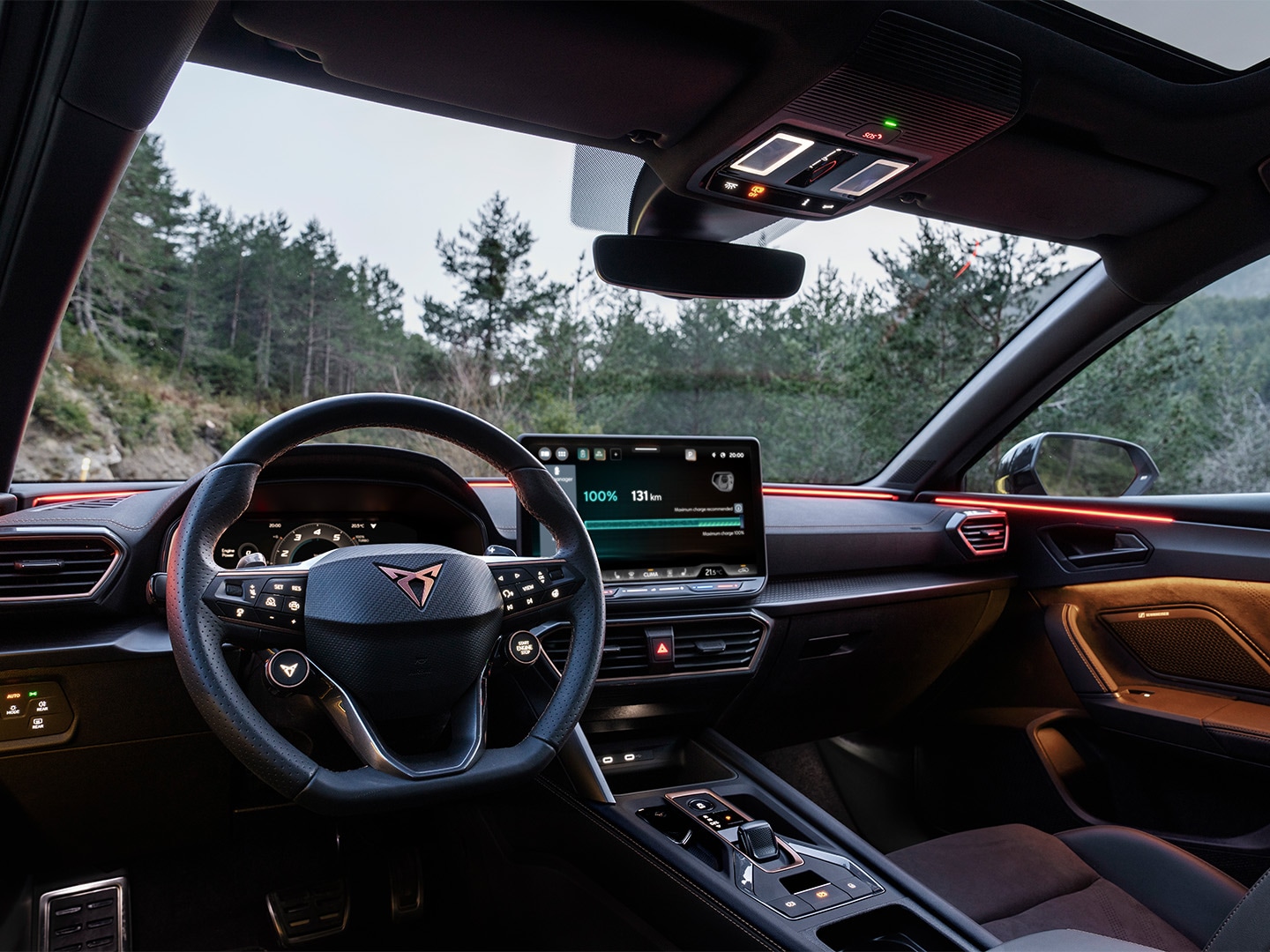 : Interior shot of the CUPRA Leon SP, featuring a driver-oriented cockpit and a digital interface, in a wooded setting.