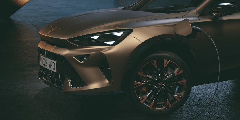 front left side view of the new century bronze matt cupra formentor 2024 with copper accent wheels, on charge, Barcelona cityscape background view at dusk